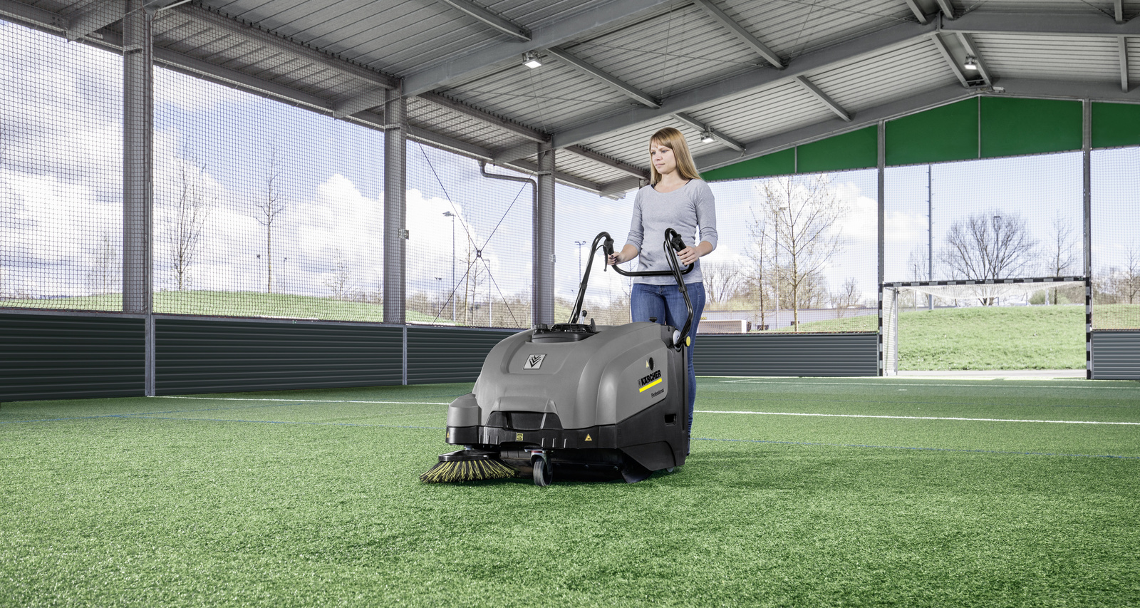 Sweeper in use A woman cleaning artificial turf with a Kärcher sweeper