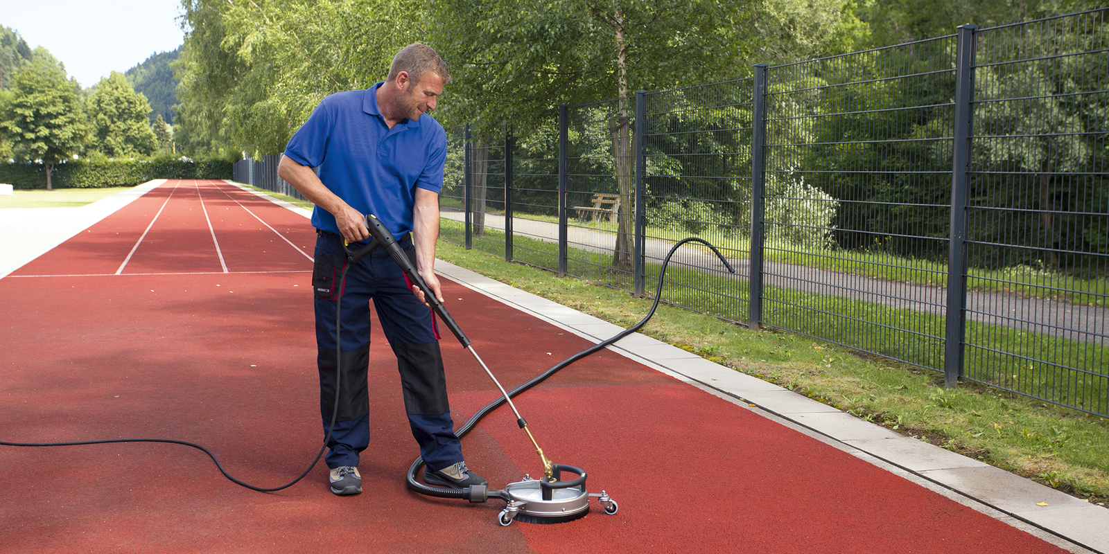 Surface cleaner in use A man cleaning a tartan track with a surface cleaner
