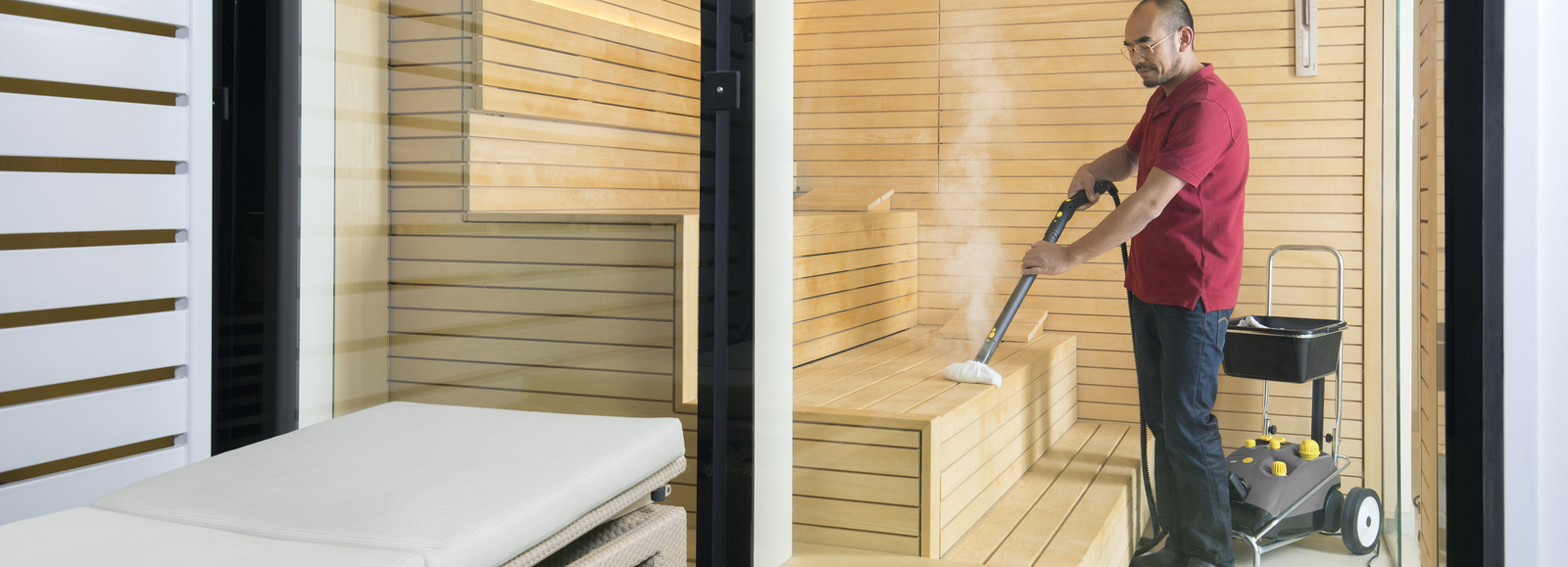 Steam cleaner in use A man cleans a sauna area with a steam cleaner from Kärcher