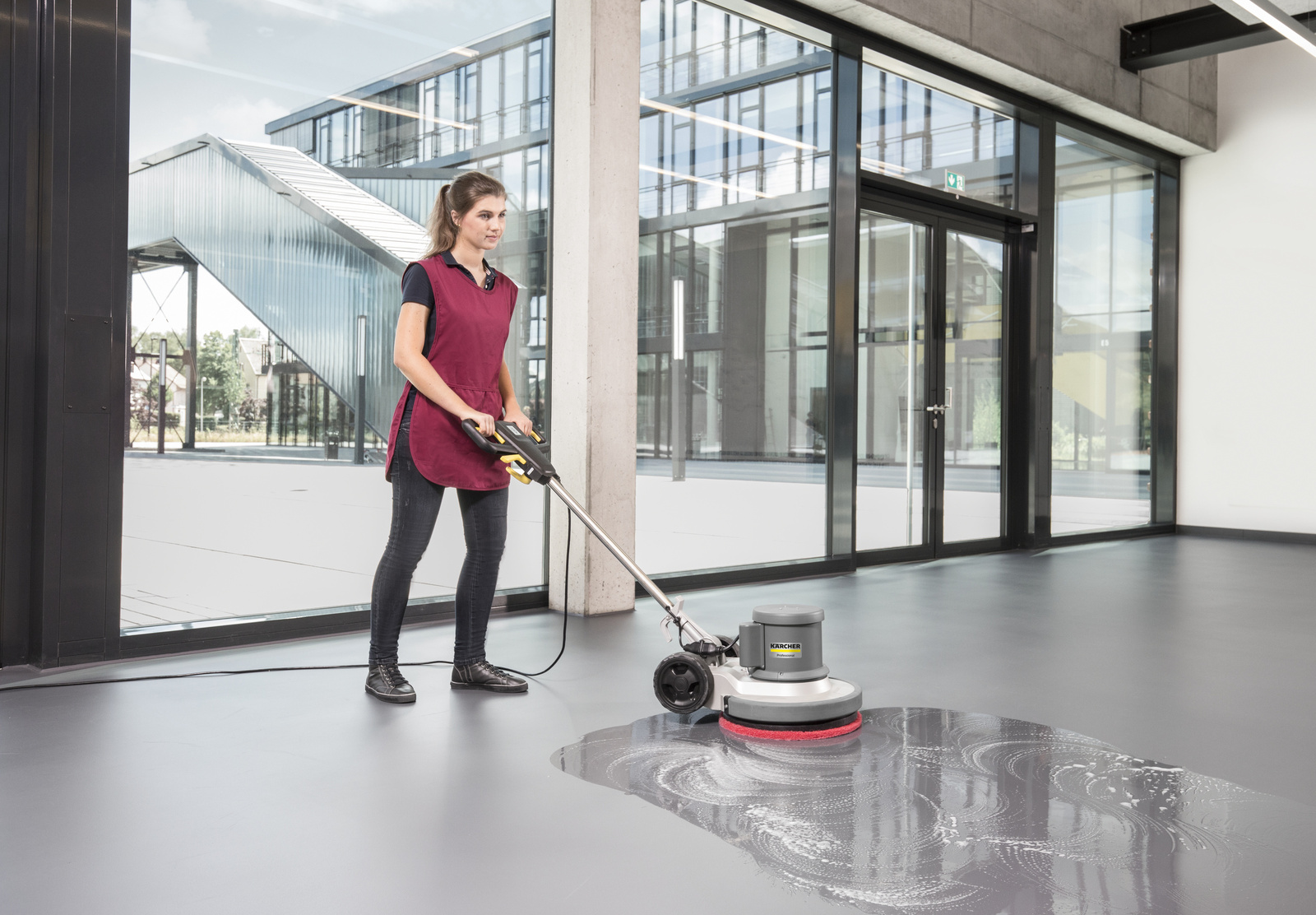 Cleaning with the scrubber dryer A woman cleaning the floor of an entrance area with a scrubber dryer.