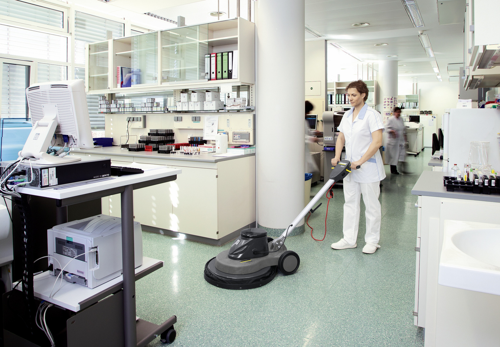 Scrubber dryer in use A woman operating a Kärcher scrubber dryer on resilient floor covering.