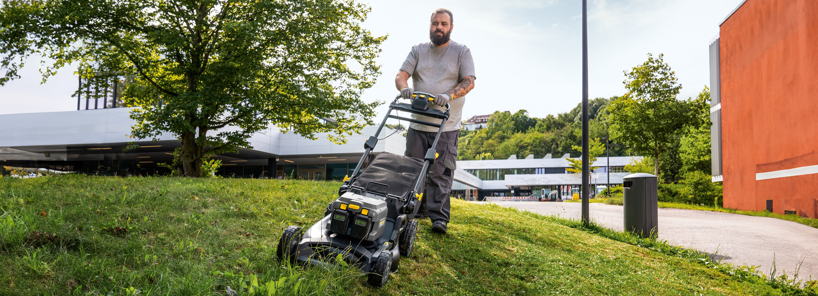 Lawn mower in use A man is mowing a green area with a lawn mower