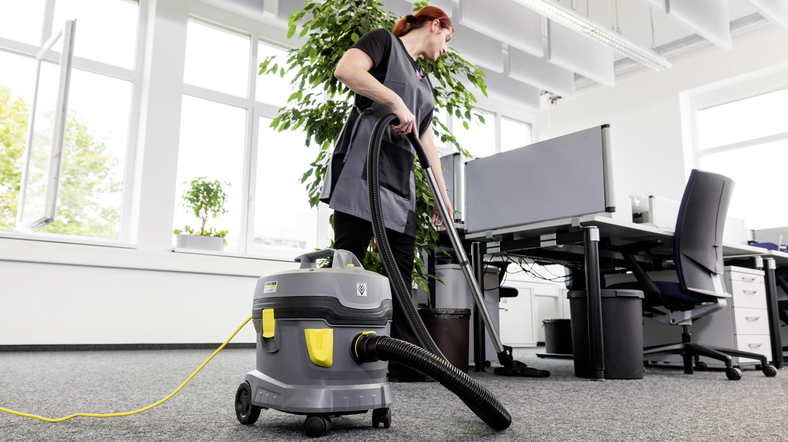 Büroreinigung Eine Person reinigt mit einem Staubsauger von Kärcher einen Büroraum