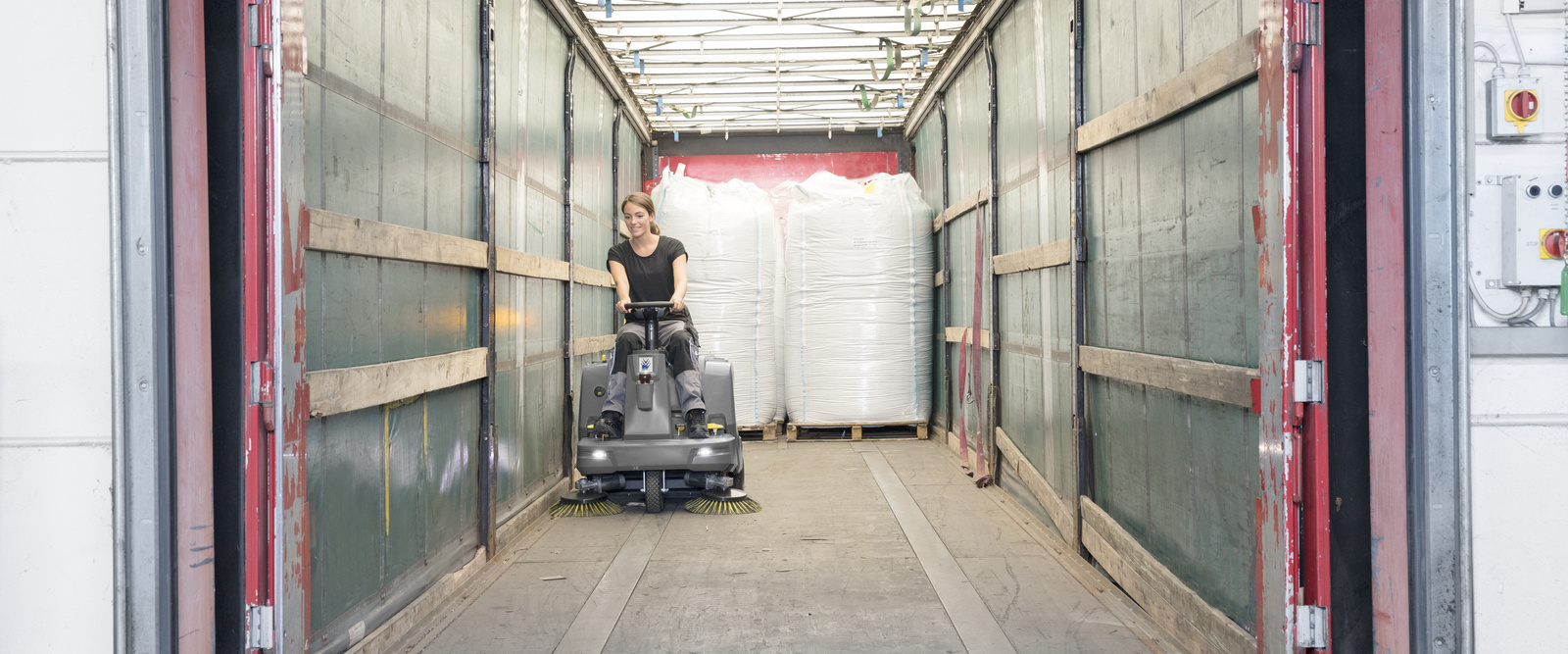 Cleaning with the vacuum sweeper A woman sits on a Kärcher vacuum sweeper