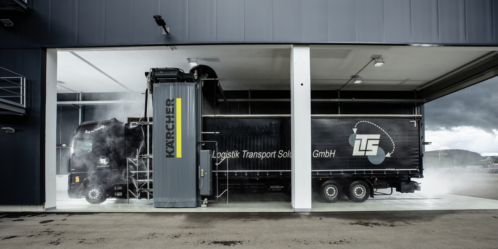 Commercial vehicle gantry wash system A truck being cleaned in a commercial vehicle gantry wash system
