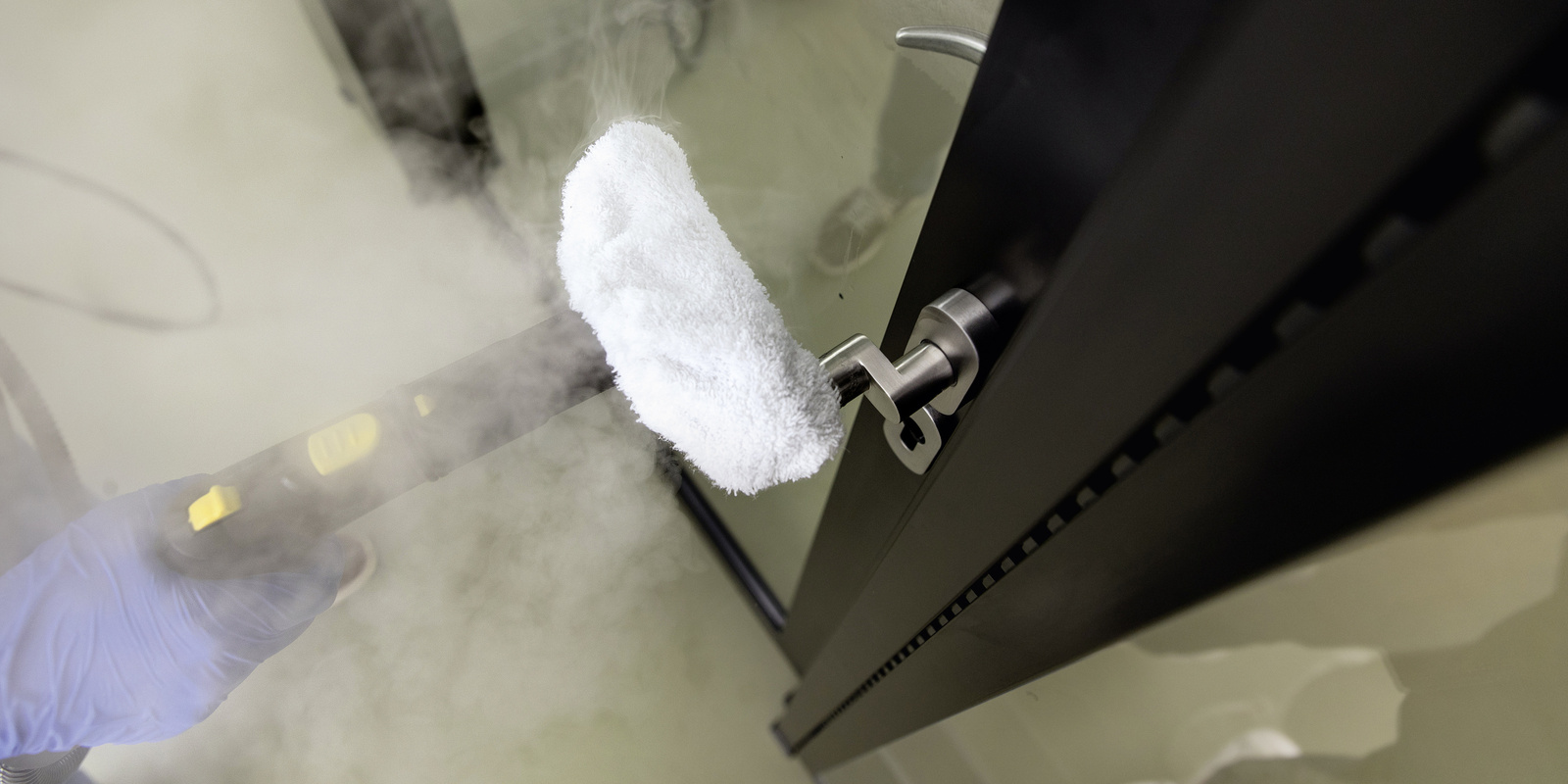 Disinfection of door handles with the steam cleaner A person disinfecting a door handle with the Kärcher steam cleaner