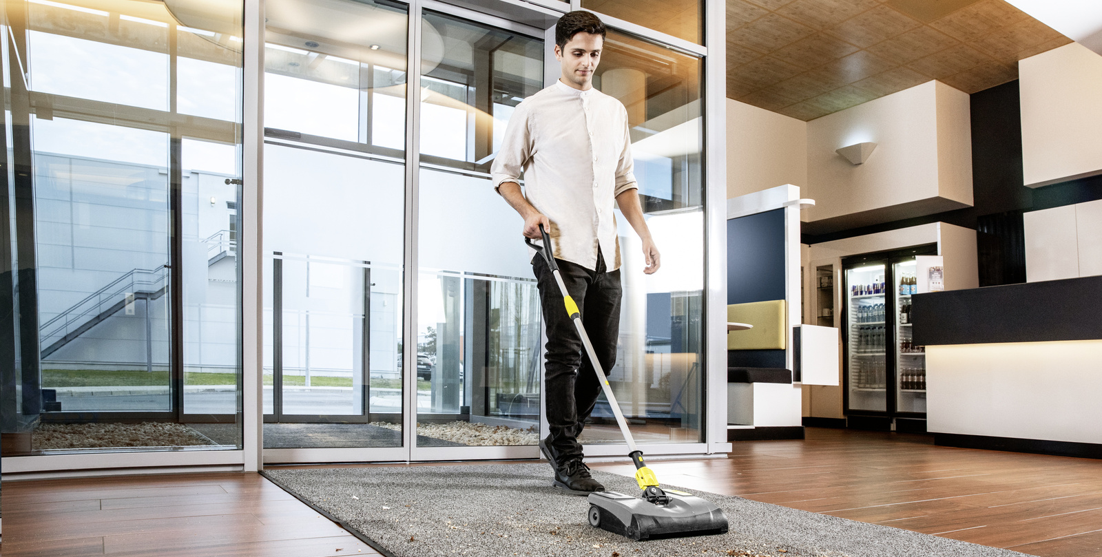 Electric broom in use A person cleaning a carpet runner in the entrance area with the electric broom