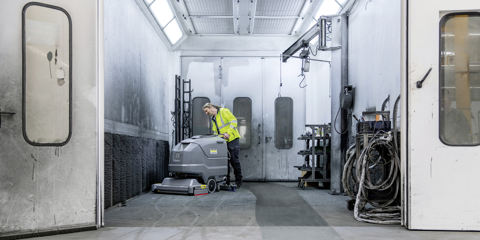 Cleaning the painting facility A man cleans a paint booth with a Kärcher sweeper