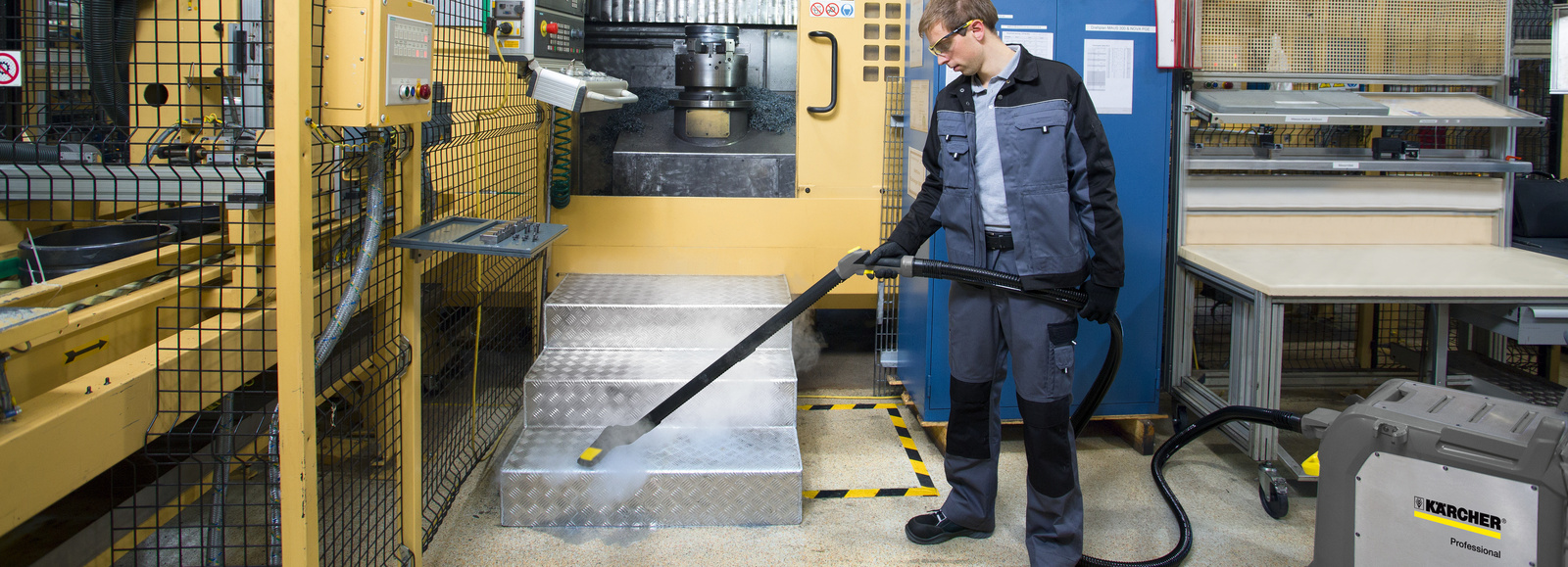 Steam cleaner in use A man cleans the stairs of a painting facility with a steam cleaner