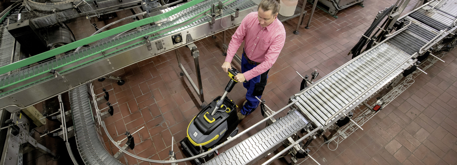 Cleaning transport belts A man cleans the industrial floor where a transport belt is located