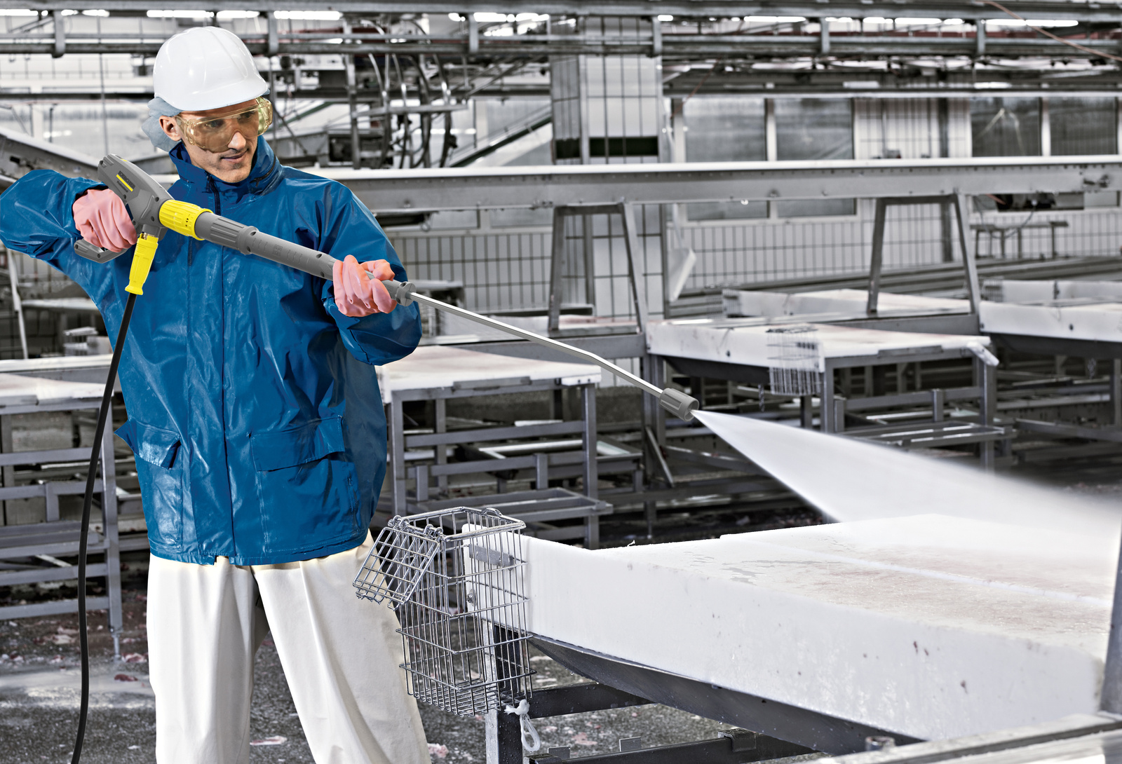 Cleaning with a pressure washer A man cleans a conveyor belt with a Kärcher pressure washer