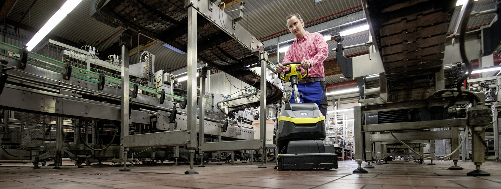 Floor cleaning with the walk-behind scrubber dryer A person cleans the floor with the walk-behind scrubber dryer