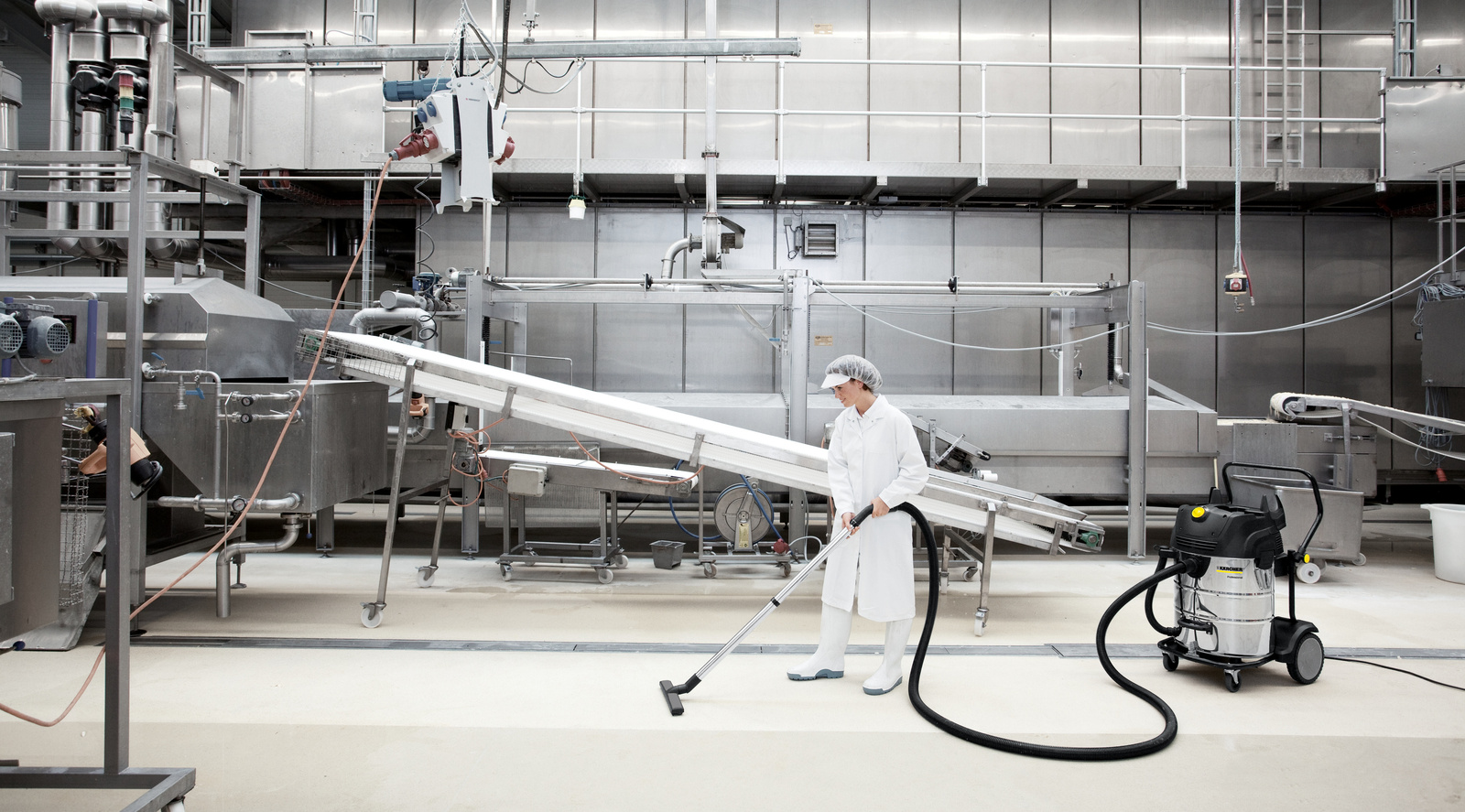 Dry vacuum cleaner in use A woman cleans an industrial floor with a dry vacuum cleaner from Kärcher