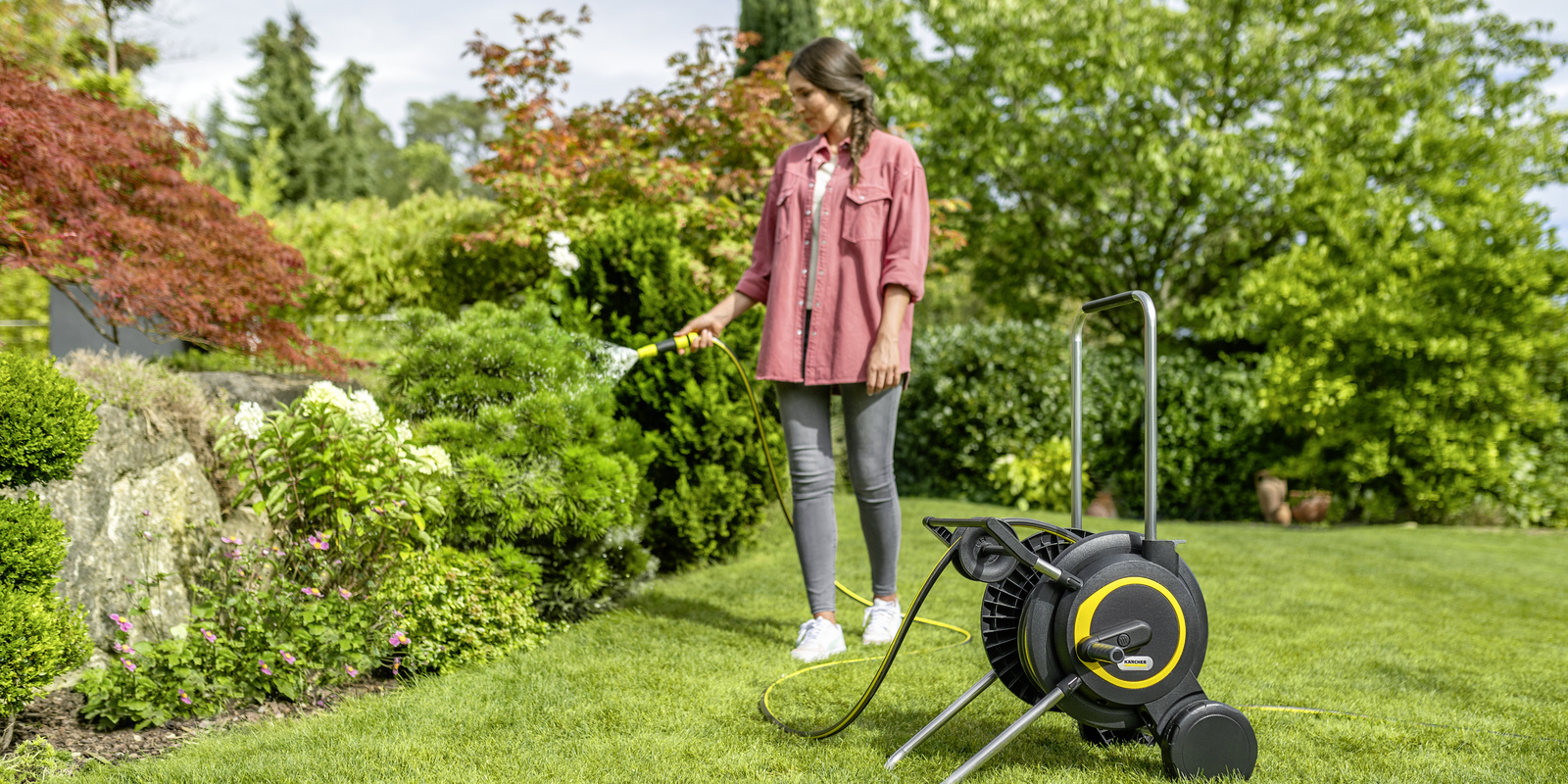 Мъж полива цветята в градината