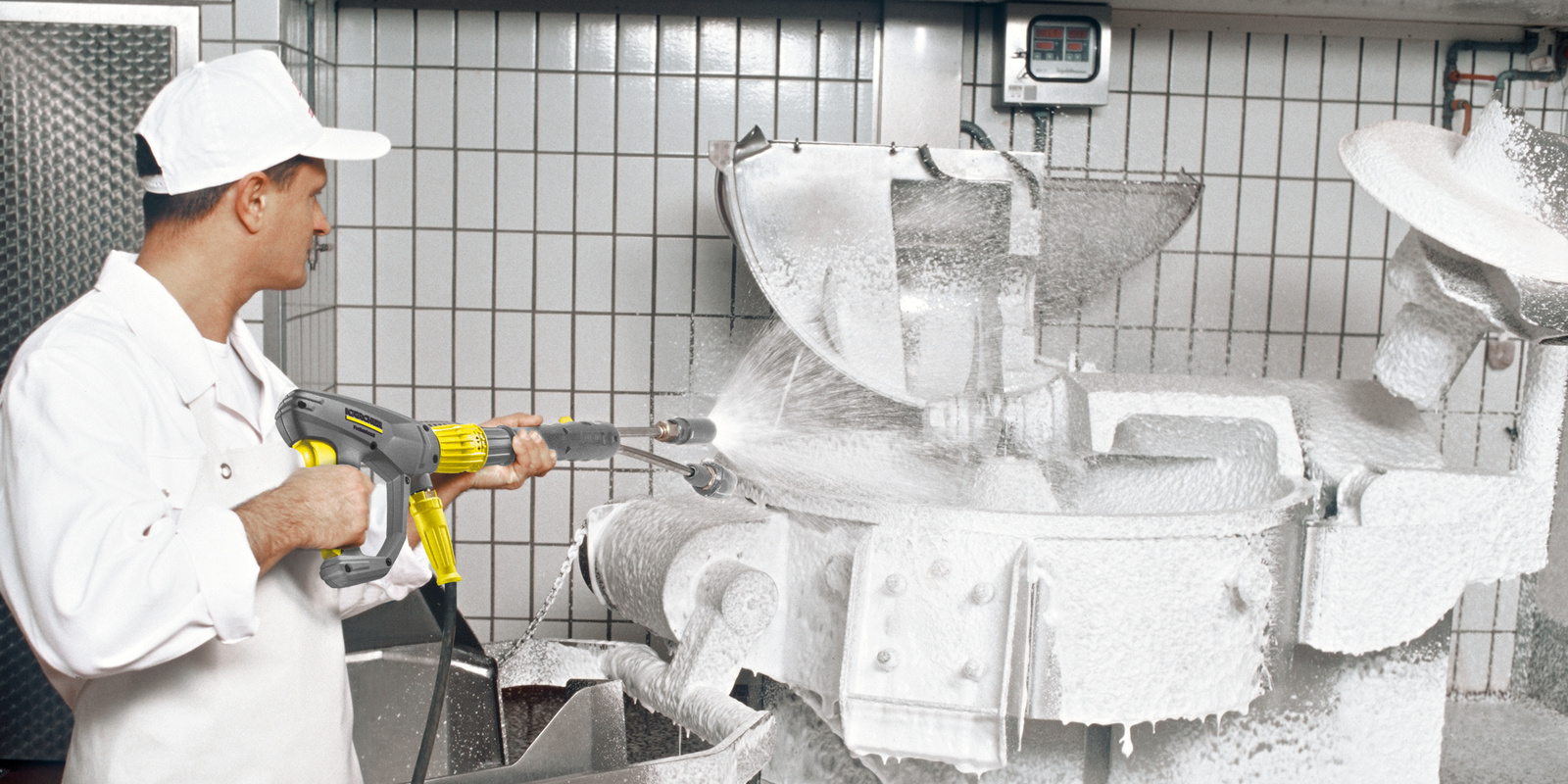 Cleaning with a high-pressure cleaner A person cleans the production facility with the high-pressure cleaner