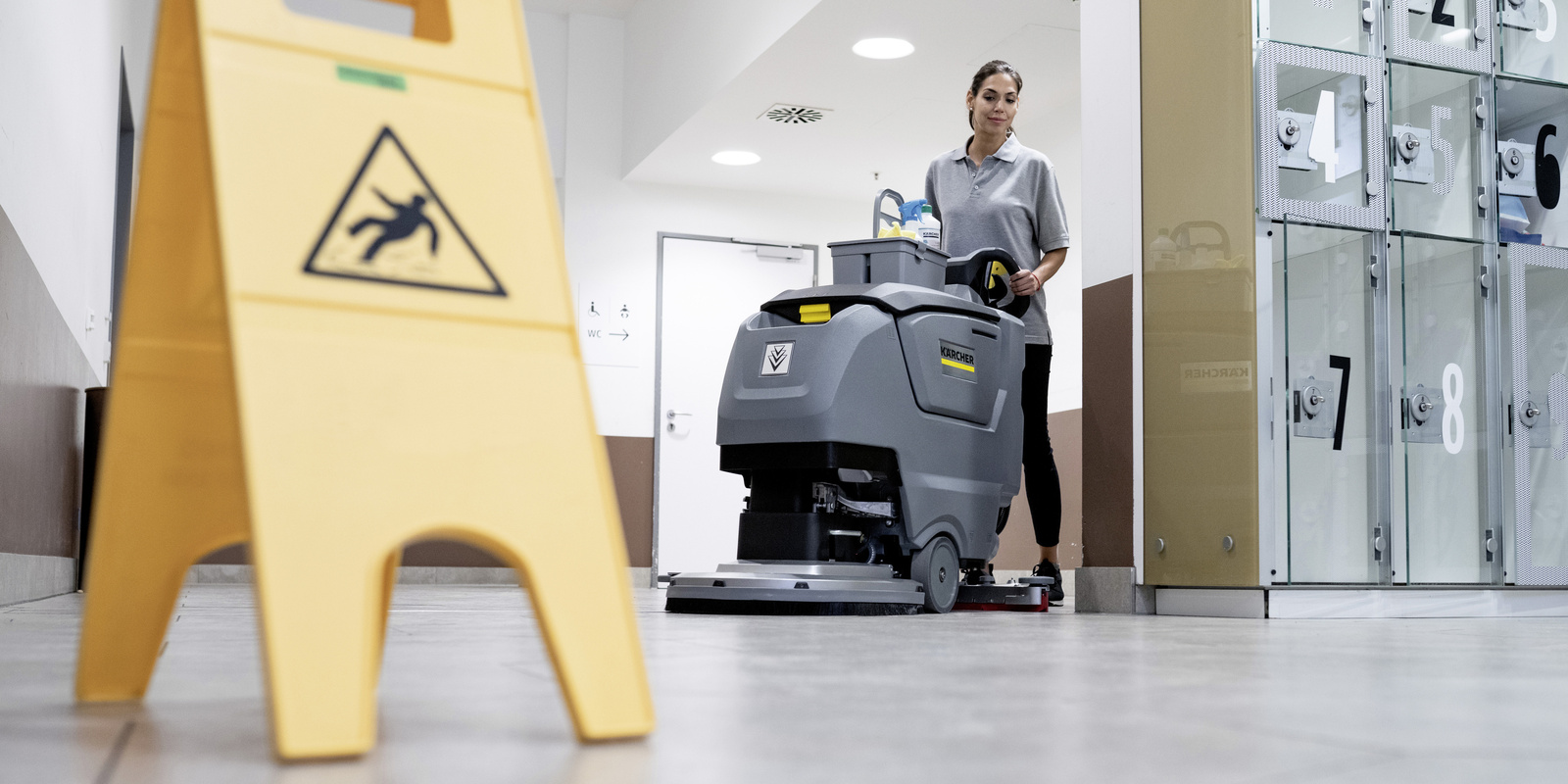 Floor cleaning with the scrubber-dryer A woman operates the scrubber-dryer