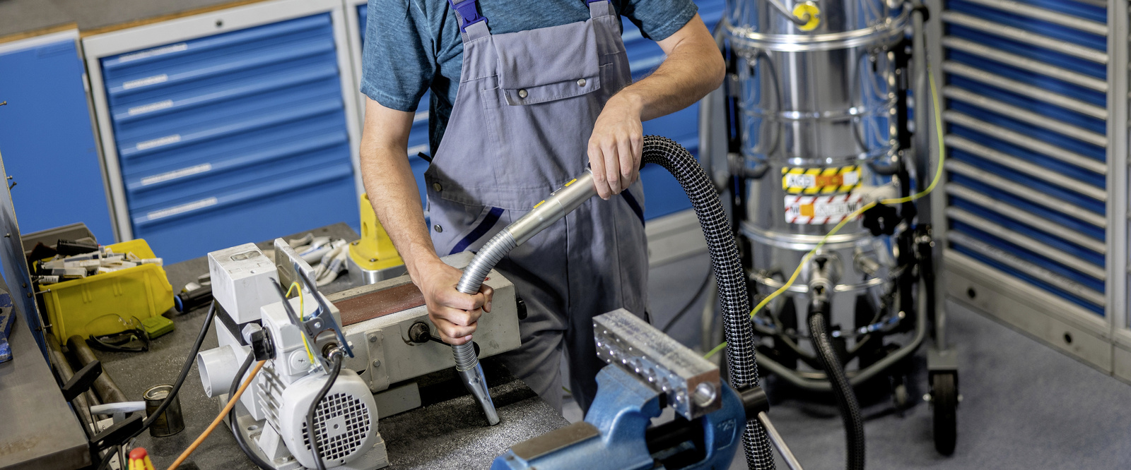 Industrial vacuum cleaner in use A man operates the industrial vacuum cleaner in the workshop