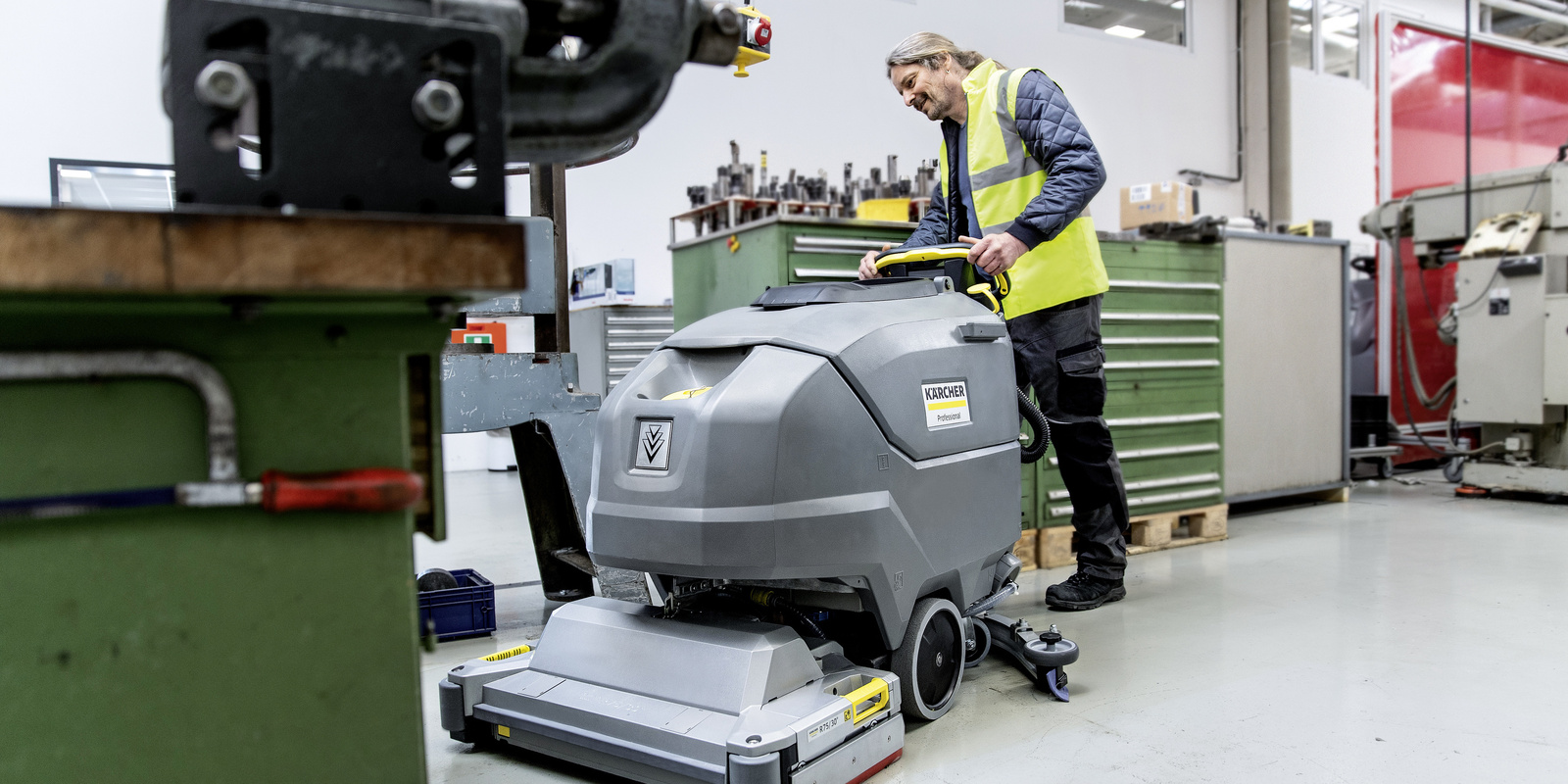 Efficient floor cleaning with the walk-behind scrubber-dryer A man cleans the floor with the walk-behind scrubber-dryer