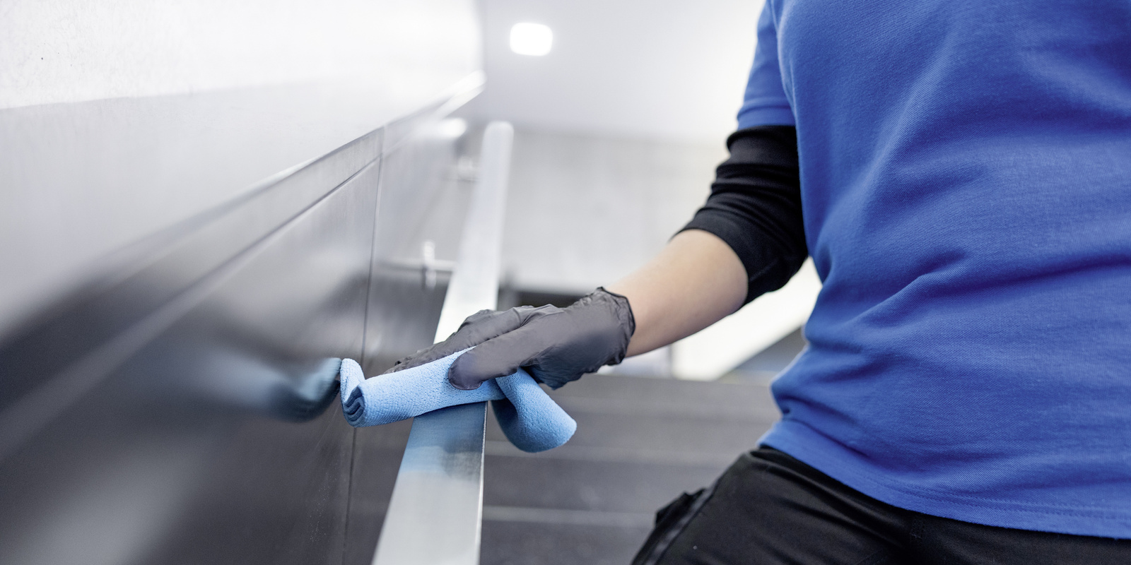 Manual cleaning between production shifts A person cleans a handrail with a microfiber cloth