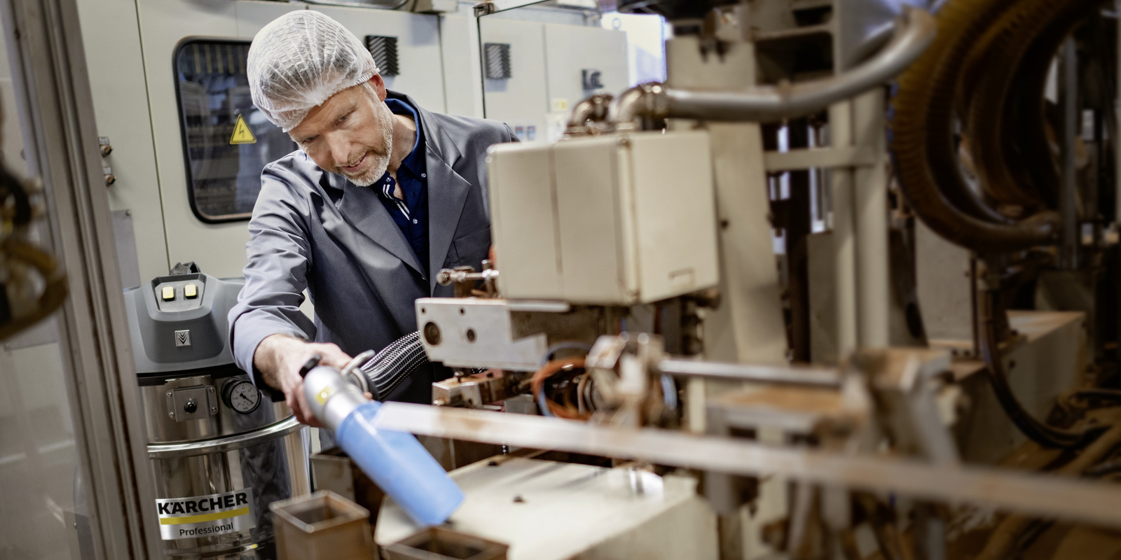 Cleaning production facilities with the industrial vacuum cleaner A man cleans a production facility with the industrial vacuum cleaner
