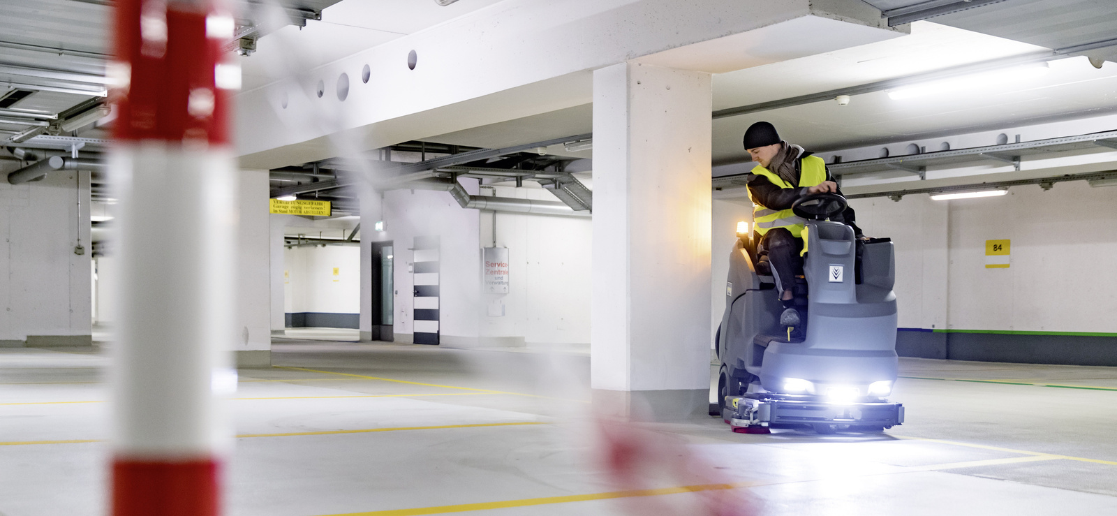 Parkhaus reinigen Eine Person sitzt auf einer Aufsitz-Kehrmaschine und reinigt einen Flughafenbereich