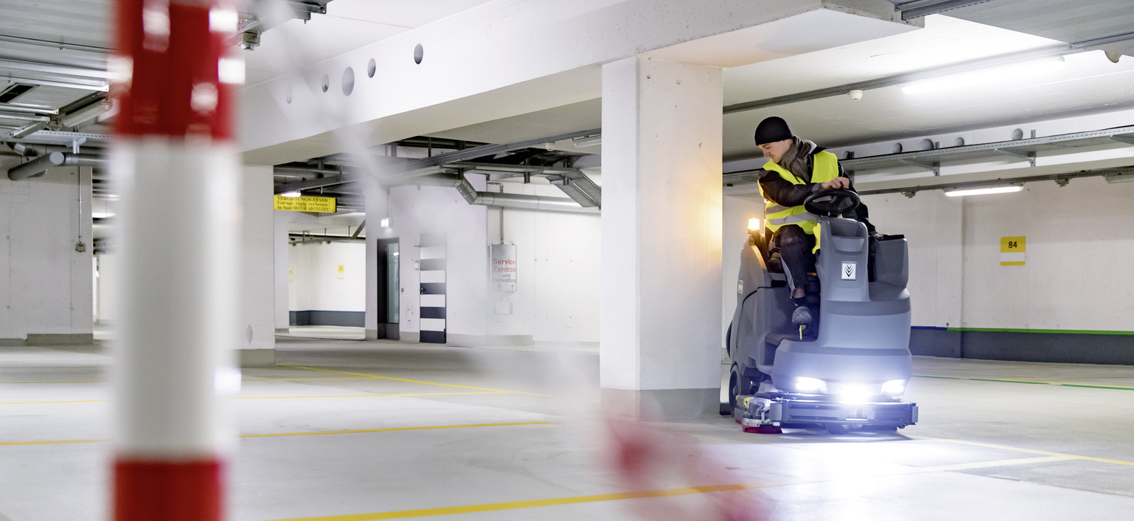 Parkhaus reinigen Eine Person sitzt auf einer Aufsitz-Kehrmaschine und reinigt einen Flughafenbereich