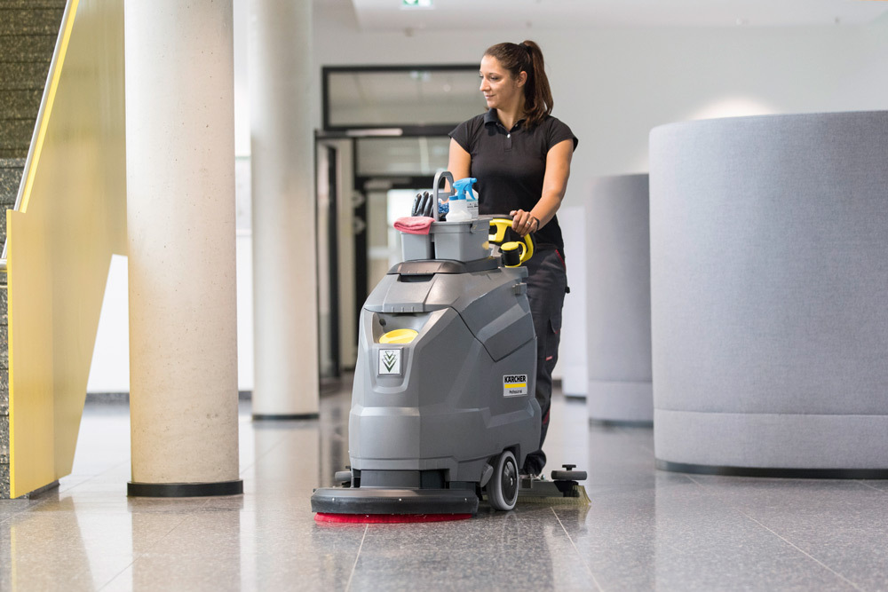 Walk-Behind Floor Scrubbers A worker uses a BD 50/50 Walk-Behind Floor Scrubber in an office entrance area