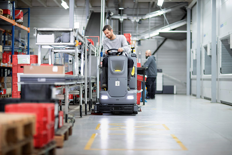 Ride-On Floor Scrubbers A worker uses a B 75/110 Ride-On Floor Scrubber in an industrial facility