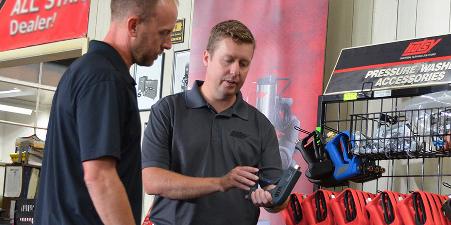 A Hotsy dealer shows a Hotsy pressure washer gun to a customer