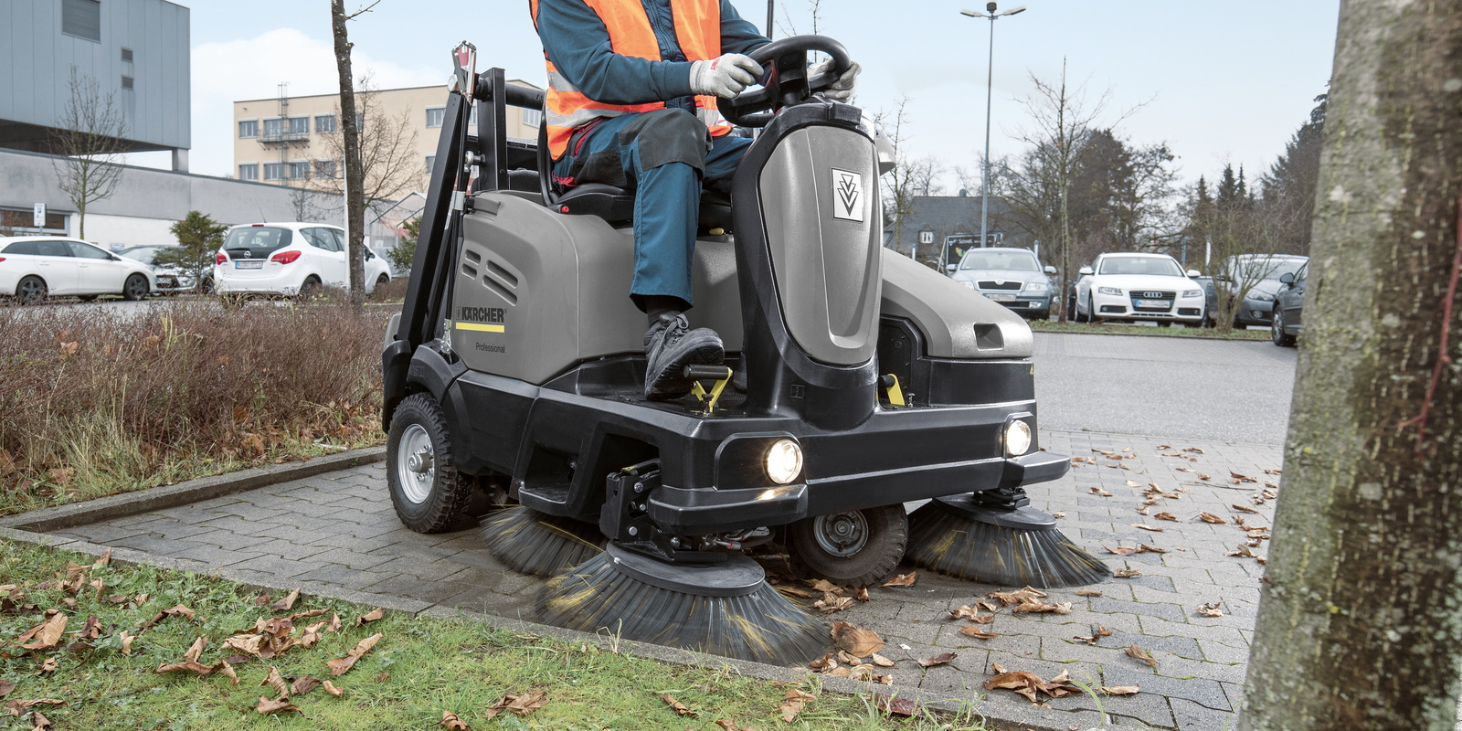 Cleaning Parking Lots and Outdoor Areas A worker uses a Kärcher ride-on sweeper to pick up leaves, dirt and debris in a parking lot.