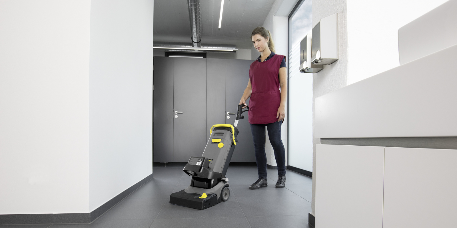 Cleaning Restrooms and Locker Rooms A contract cleaner cleans floors in a gym changing room.
