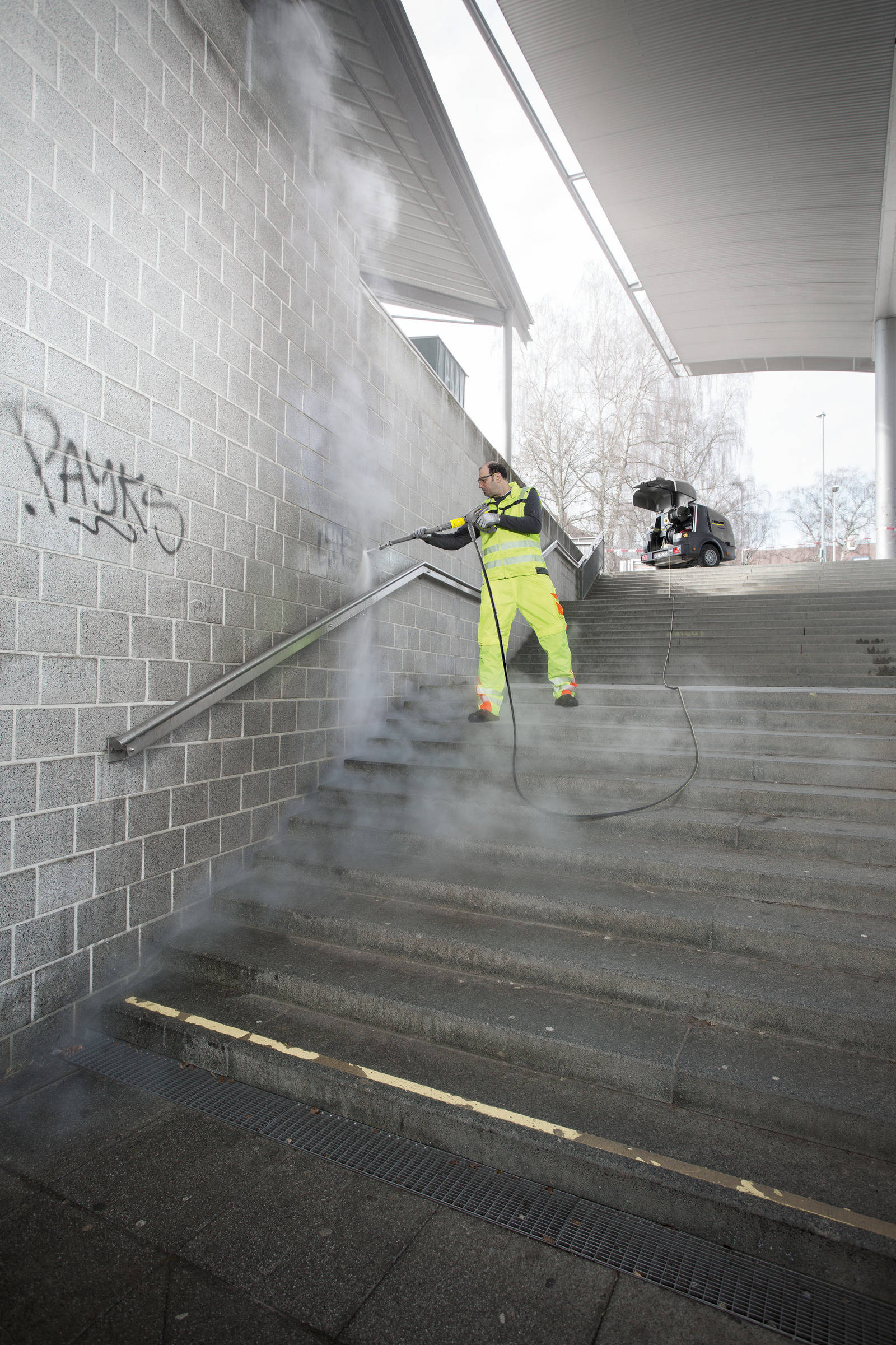 eine Person in Schutzkleidung reinigt mit einem Kärcher Höchstdruckreiniger eine Schalung