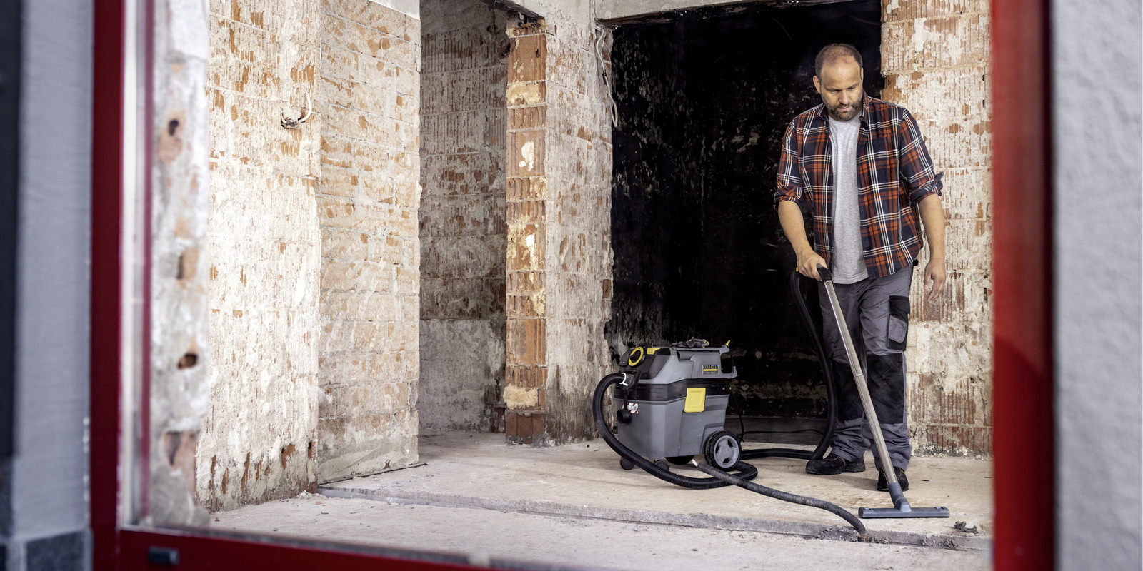 Bauendreinigung eine Person reinigt den Rohbau-Fußboden mit einem Kärcher Nass-/Trockensauger