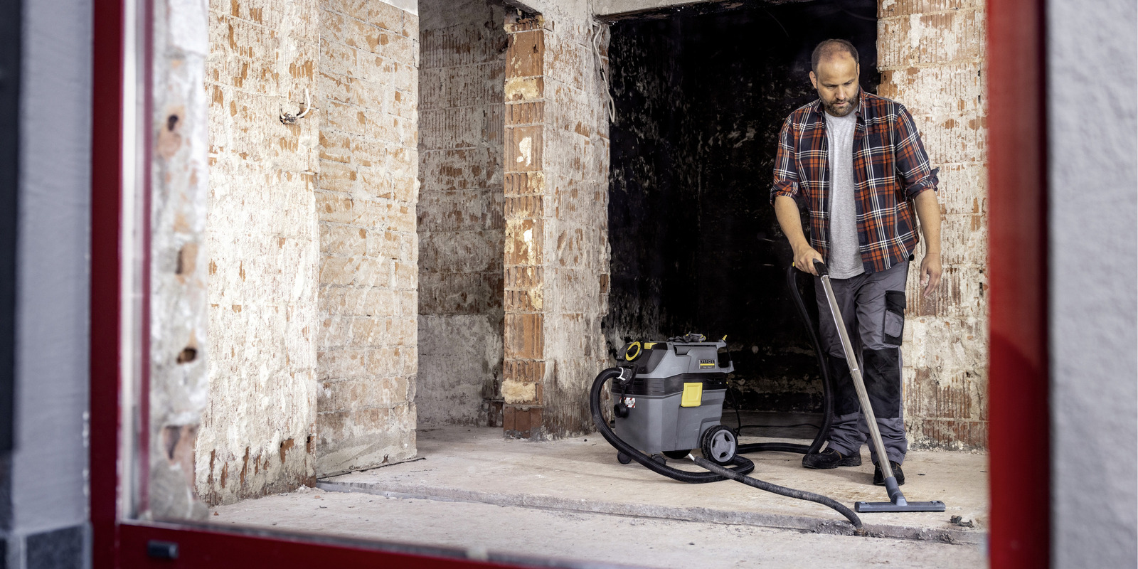 Bauendreinigung eine Person reinigt den Rohbau-Fußboden mit einem Kärcher Nass-/Trockensauger