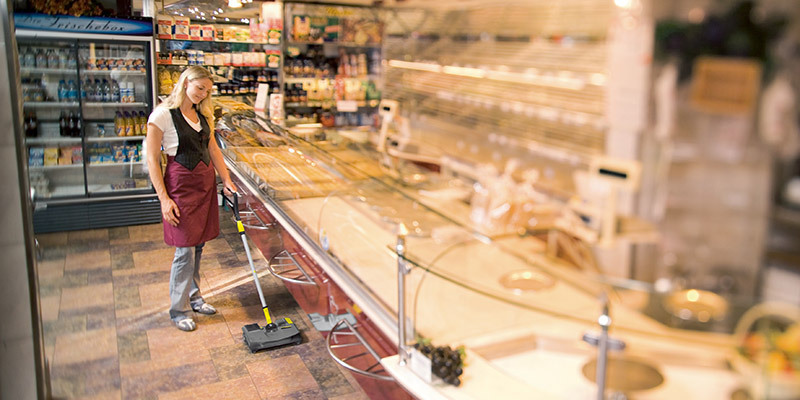 A worker uses a compact walk-behind sweeper to efficiently clean inside a bakery