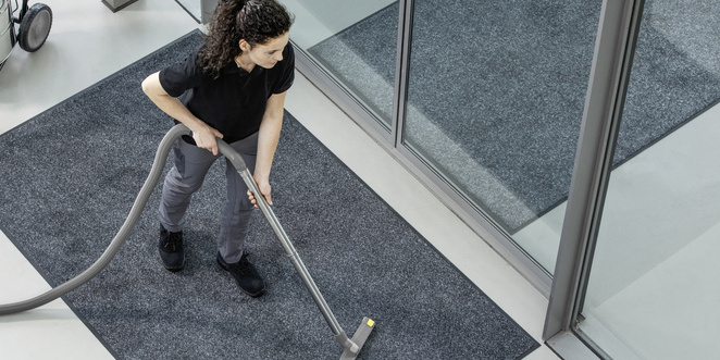 A person is cleaning the entrance area using a vacuum cleaner