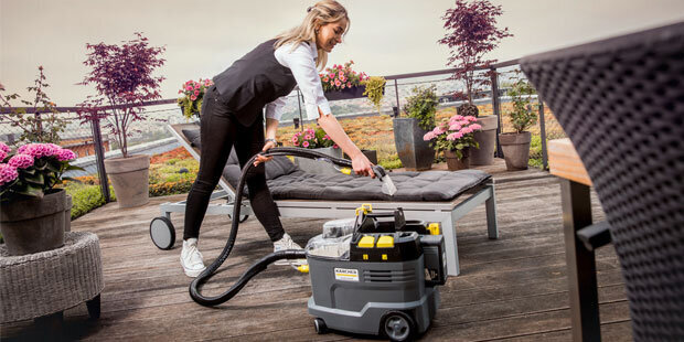 Kärcher Compact Extractors A worker uses a Kärcher Puzzi 8/1 C compact extractor on outdoor furniture at a hotel