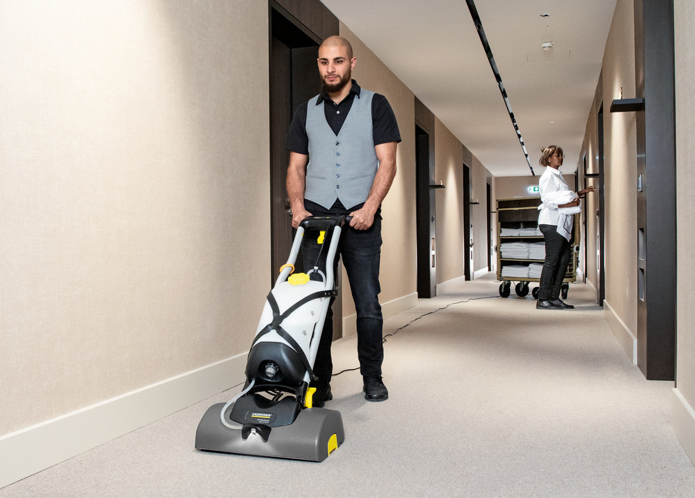 Kärcher's iCapsol technology A hotel worker uses the iCapsol Deluxe carpet extractor in a long hallway