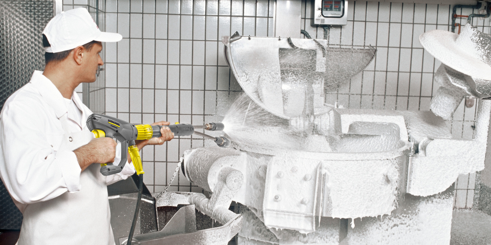Food industry Man cleans industrial mixer with high-pressure cleaner