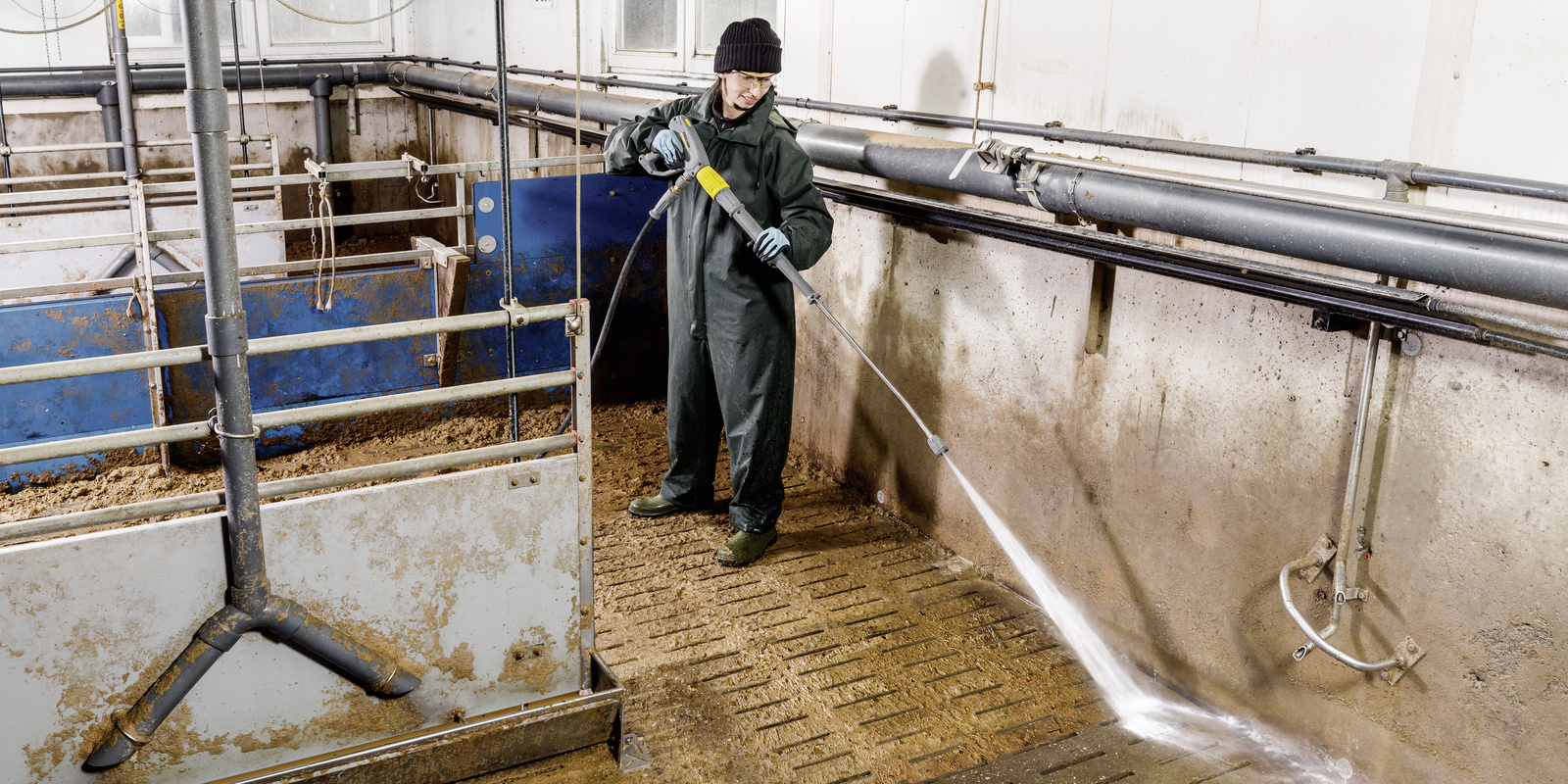 Agriculture Man cleans stall with high-pressure cleaner