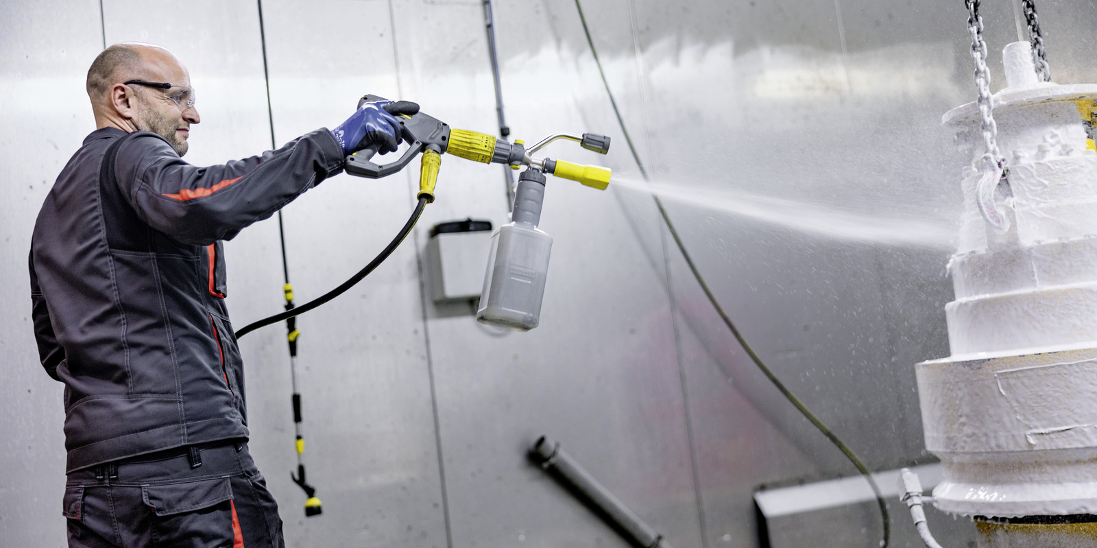 Accessories for stationary high-pressure cleaners Man sprays component with foam