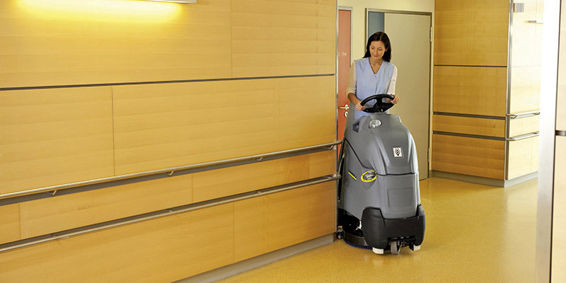A worker uses a Chariot stand-on floor scrubber to quietly clean hospital floors during daytime hours