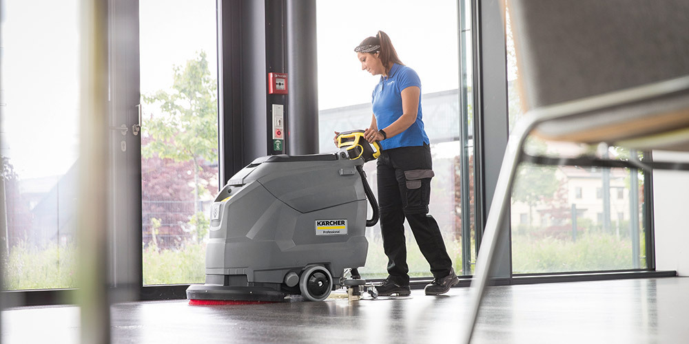 A worker cleans floors with a Kärcher Professional Floor Scrubber