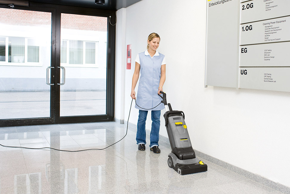 A worker cleans floors with natural stone using a Kärcher compact walk-behind floor scrubber
