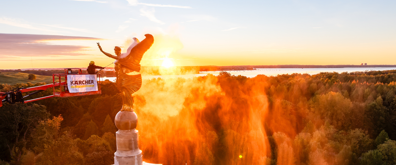 Man On Boom Lift Pressure Washing Statue Of A Golden Angel