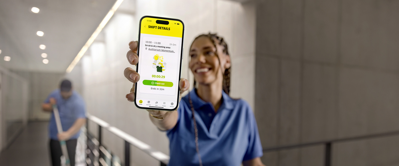 Smiling cleaning professional showing Connected Cleaning mobile app with running shift