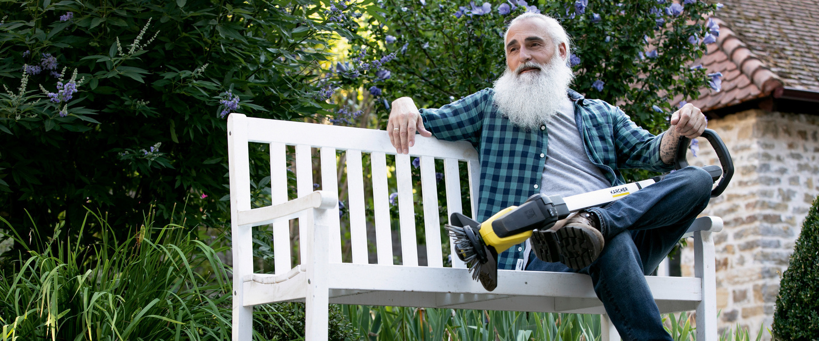 Man with battery weed remover sitting on bench in the garden