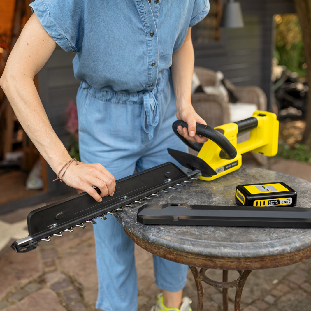 Person benutzt den Schnittgutkehrer der Kärcher Akku-Heckenschere