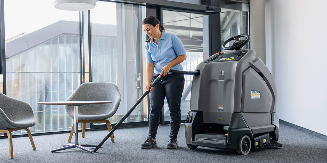A worker cleans the interior of an office building with Kärcher cleaning equipment