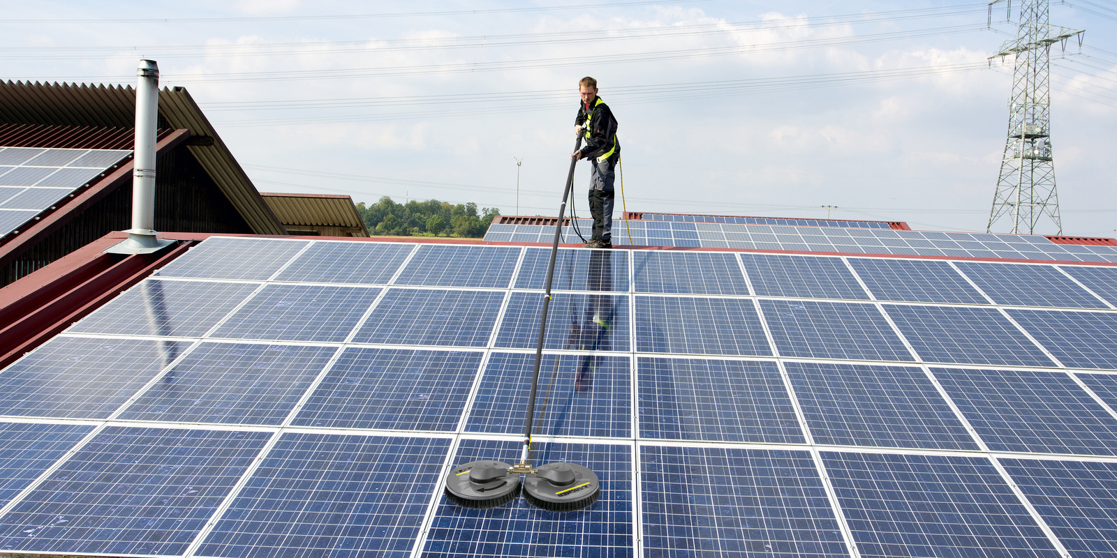 A worker cleans solar panels on top of a building